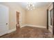 A neutral bedroom features an elegant light fixture and view to an ensuite bathroom at 7029 Pebble Bay Dr, Denver, NC 28037