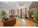 A cozy living room features hardwood floors, a stone fireplace, comfortable seating, and bright windows at 7029 Pebble Bay Dr, Denver, NC 28037