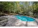 Beautiful in-ground pool surrounded by lush greenery and a stone paver deck in a private backyard oasis at 7029 Pebble Bay Dr, Denver, NC 28037