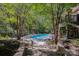 A backyard swimming pool is surrounded by a stone patio and lush greenery, offering a private outdoor retreat at 7029 Pebble Bay Dr, Denver, NC 28037