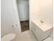 Marble tiled bathroom with a new toilet, modern vanity, and door leading to another room at 125 S Ervin Ave, Newton, NC 28658