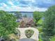 Stunning waterfront home featuring stone exterior, circular driveway, mature trees, and serene lake views at 18212 Pompano Pl, Cornelius, NC 28031