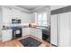 The kitchen has white cabinetry, black appliances, light wood floors and modern backsplash at 18212 Pompano Pl, Cornelius, NC 28031
