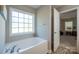 Bright bathroom showcasing a soaking tub under a window and a doorway to another room at 5039 Penn Rd, Iron Station, NC 28080