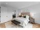 Stylish main bedroom featuring hardwood floors, tufted headboard, bench seat and modern lighting at 217 Keswick Ave, Charlotte, NC 28206