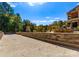 Gravel area with a stone wall and view of an outdoor terrace with lush landscaping and blue skies at 2723 Providence Pine Ln, Charlotte, NC 28270