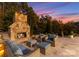 Cozy outdoor fireplace with stone surround, comfortable seating, and a serene wooded backdrop at twilight at 2723 Providence Pine Ln, Charlotte, NC 28270