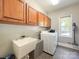 A functional laundry room with modern washing machine, sink and wooden cabinets at 128 Archbell Point Ln, Mooresville, NC 28117