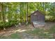 Wooden storage shed with a fire pit area, nestled in a wooded setting at 128 Archbell Point Ln, Mooresville, NC 28117