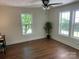 Bright bedroom with hardwood flooring, ceiling fan, and views of outside landscaping from the windows at 7608 Kershaw Camden Hwy, Kershaw, SC 29067