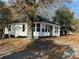 Charming home with a white exterior, black roof, brick chimney, and surrounding trees on a leaf-covered lot at 7608 Kershaw Camden Hwy, Kershaw, SC 29067