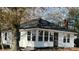 Charming cottage-style home with a black roof, white siding, and a welcoming sunroom extension at 7608 Kershaw Camden Hwy, Kershaw, SC 29067