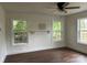 Bright living room featuring three windows, hardwood floors, a ceiling fan, and a classic white-painted shelf at 7608 Kershaw Camden Hwy, Kershaw, SC 29067