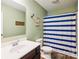 Bright bathroom with blue striped shower curtain and wood look vinyl flooring at 1176 Whitehall Hill Rd, York, SC 29745