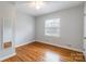 Bedroom featuring hardwood floors, a window for natural light, and a full-length mirror at 1166 Montford Dr, Charlotte, NC 28209