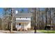 Quaint white two-story home featuring a welcoming front porch, round accent windows, and nestled among mature trees at 1062 Full Count Ln, Lancaster, SC 29720