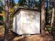 Exterior of a white storage shed with tan trim nestled amongst trees in the backyard at 1216 Stallion Ln, Lancaster, SC 29720