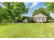 Lawn view of home and outbuilding with a basketball court, framed by mature trees offering privacy and recreational space at 18210 Pompano Pl, Cornelius, NC 28031