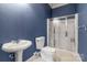 Cozy bathroom with unique blue textured walls, a pedestal sink, toilet, and glass-enclosed shower at 18210 Pompano Pl, Cornelius, NC 28031