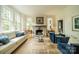 Bright living room with fireplace, hardwood floors, large windows, comfortable couch, and blue velvet chairs at 1919 Kensal Ct, Charlotte, NC 28211