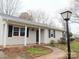 Ranch style home with light beige siding, white columns, and a landscaped front yard at 5105 Chelsey Ln, Monroe, NC 28110