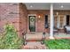 Inviting front porch features brick accents, black door with glass, decorative lanterns, and lovely greenery at 271 Lockhard Cir, Troutman, NC 28166