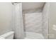 Bright bathroom featuring neutral tiles and a white shower curtain over a clean, white tub at 11429 Spreading Oak Ln, Charlotte, NC 28226