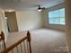 This bonus room has carpet floors, a ceiling fan, a window, and a staircase at 6416 Red Maple Dr, Charlotte, NC 28277