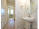 Bathroom features a white pedestal sink, decorative mirror, and a view of the adjoining room at 1200 Meander Ln, Waxhaw, NC 28173