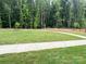 Expansive green space bordered by a walking path, with a lush tree line behind at 12110 Storm Ln # 49, Charlotte, NC 28277