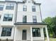 Modern farmhouse exterior with white siding, black trim, covered porch, and gray front door at 12126 Storm Ln # 53, Charlotte, NC 28277