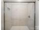 Luxurious tiled shower with glass door, rainfall shower head, and built-in shelving at 9247 Eleanor Dr, Charlotte, NC 28214