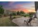 Beautiful backyard with a large patio, mature trees, and lush landscaping under a vibrant sunset sky at 7095 Sunset Crater Pl, Lancaster, SC 29720