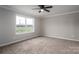 Cozy bedroom with neutral carpet, ceiling fan, and a large window offering natural light and outdoor views at 9303 Reepsville Rd, Vale, NC 28168