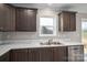 Close-up of the kitchen sink area, featuring modern appliances, a window, and dark wood cabinetry at 9303 Reepsville Rd, Vale, NC 28168