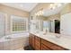 Bright bathroom featuring a dual sink vanity, soaking tub, and glass block window for natural light and privacy at 4225 Cheshire Glen Dr, Monroe, NC 28110