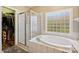 Sunlit bathroom showcasing a tub with glass block window, glass shower, and walk-in closet at 4225 Cheshire Glen Dr, Monroe, NC 28110