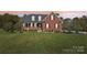 Inviting red brick home with a well-manicured lawn and charming architectural details at 4225 Cheshire Glen Dr, Monroe, NC 28110