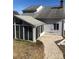 Rear view of house featuring a sunroom addition and a gravel patio area at 8540 Indian Summer Trl, Harrisburg, NC 28075