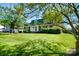Beautiful front yard with green grass, bushes, mature trees and one story brick home at 1018 Carysbrook Ln, Charlotte, NC 28217