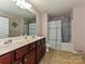 This bathroom offers a double vanity, tile floors, and a tub with a shower at 14121 Winford Ln, Charlotte, NC 28262