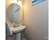 Powder room features a pedestal sink, a round mirror, neutral walls, and a towel hanging on a towel bar at 14121 Winford Ln, Charlotte, NC 28262