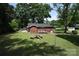 A shady backyard featuring a brick home with a deck, picnic table, and mature trees at 2427 Rhyneland St, Gastonia, NC 28054