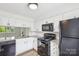 Bright kitchen features white cabinets, granite countertops and black appliances at 9424 Lexington Cir # F, Charlotte, NC 28213