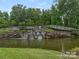 Scenic view of a stone water feature in a pond, surrounded by lush greenery and trees on a sunny day at 6296 Raven Rock Dr # 725, Denver, NC 28037