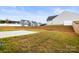 A grassy backyard with a concrete patio and a view of neighboring homes under a blue sky at 159 Tanner Loop, Troutman, NC 28166