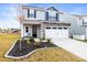 Two-story home showcasing neutral siding, stone accents, a two-car garage, and a professionally landscaped front yard at 159 Tanner Loop, Troutman, NC 28166