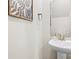 Elegant powder room featuring a pedestal sink, modern faucet, framed botanical art, and neutral decor at 159 Tanner Loop, Troutman, NC 28166
