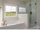 Bright bathroom with a soaking tub and a glass-enclosed shower, offering modern fixtures and natural light at 3034 Buffet Ln, Monroe, NC 28110