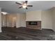 Open living room with a ceiling fan, fireplace with a brick hearth, and dark wood flooring, creating a warm ambiance at 3034 Buffet Ln, Monroe, NC 28110